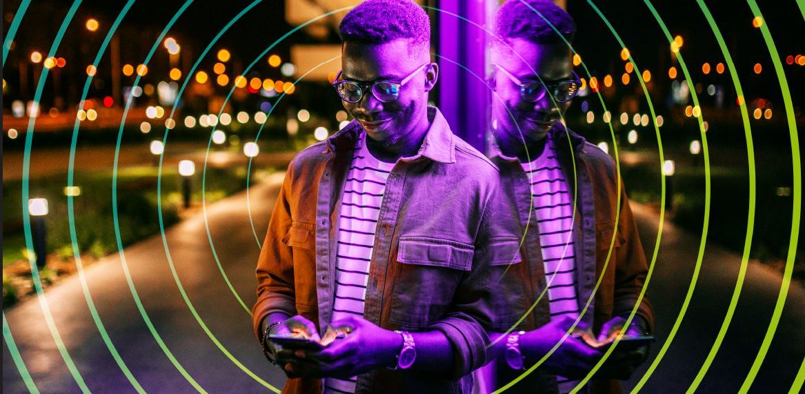 A man on his mobile phone with city lights behind him.